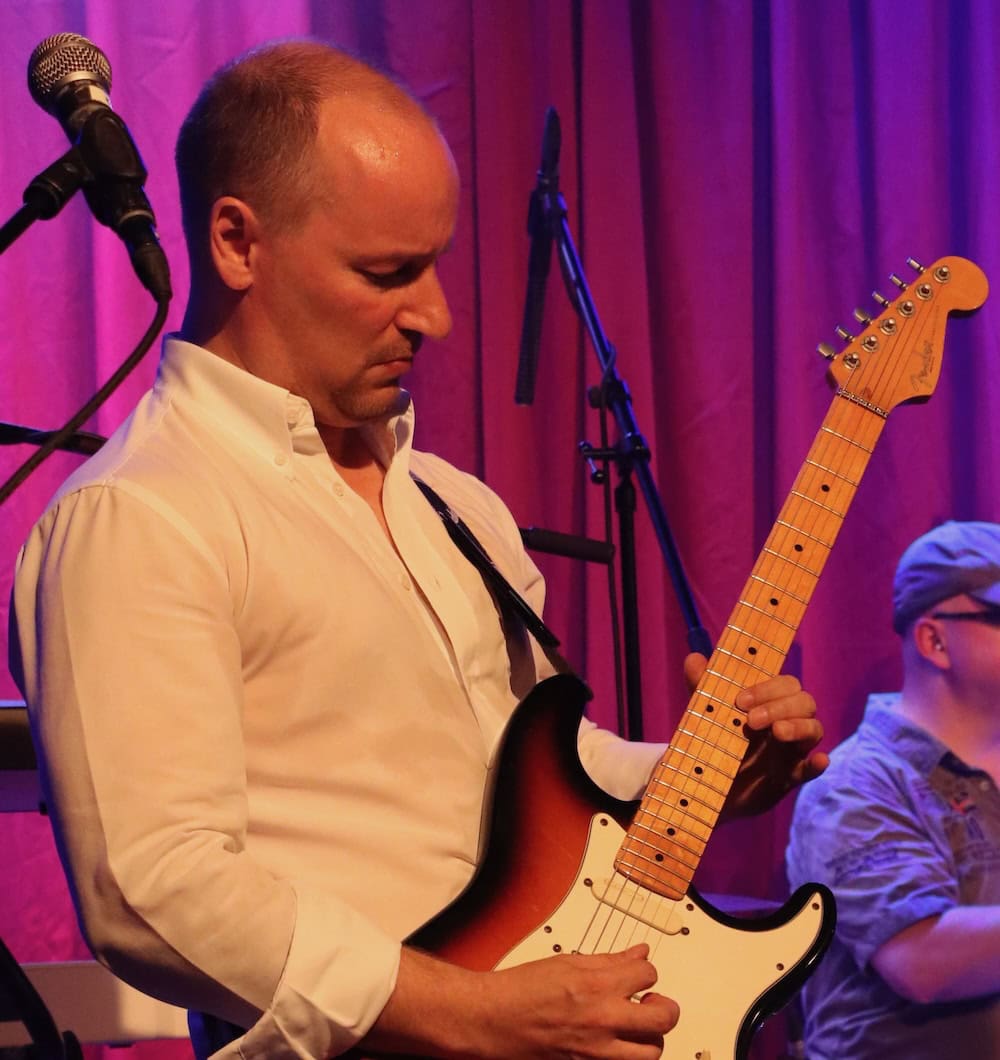 Mann spielt E-Gitarre auf der Bühne.