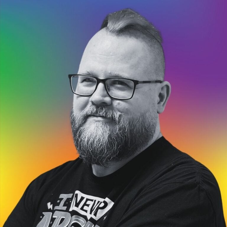 Person mit Bart vor buntem Hintergrund