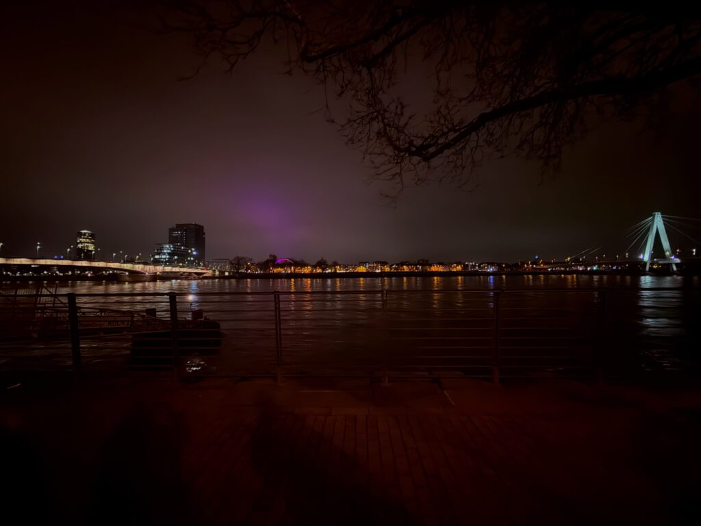 Nachtaufnahme der Kölner Skyline mit beleuchteter Brücke.