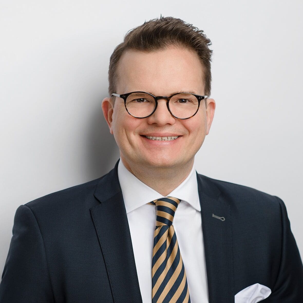 Lächelnder Mann in Anzug mit Krawatte.